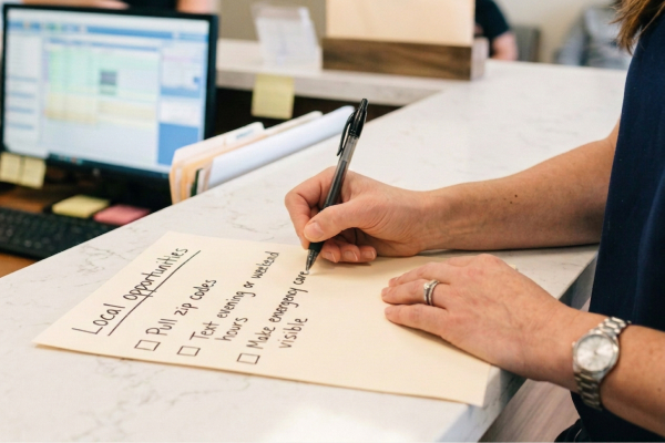 Dental practice team member writing a checklist of local marketing opportunities, including reviews and Google Business Profile